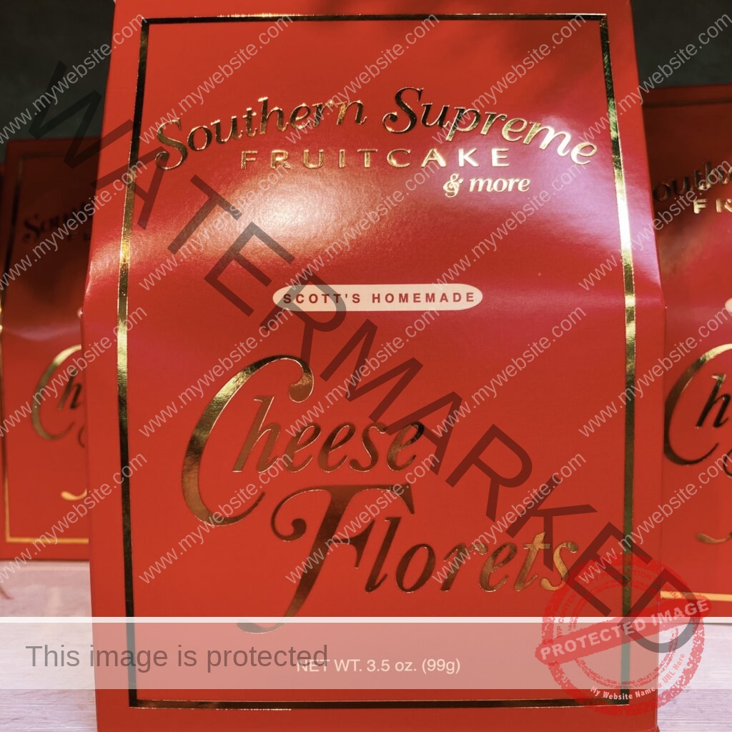A glossy red gable-top gift box with gold lettering reading "Southern Supreme Fruitcake & more," "Scott's Homemade," and "Cheese Florets," with a net weight of 3.5 oz (99g). Identical boxes are stacked behind it.
