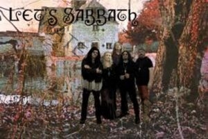 A promotional band photo with ornate text reading "Let's Sabbath" across the top. Five people in dark, gothic-style clothing stand together outdoors among autumn-colored trees and fallen leaves, with a stone building and water in the background. The image has a moody, slightly weathered look.