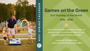 Promotional graphic for "Games on the Green," part of the NoVi Spring Calendar, held the 2nd Thursday of the month from 4PM to 8PM. The left side features a photograph of a man and two young boys playing cornhole on a grassy lawn. The man, with short dark hair and a beard, wears a navy polo shirt and khaki shorts and is bent slightly forward holding a bean bag. To his left, a small boy in a yellow t-shirt and denim shorts holds a gray bean bag in both hands. To his right, a slightly older boy in a light blue polo and khaki shorts throws his arms up mid-celebration. A blue and white cornhole board branded "Preston Development Company" sits on the grass in the foreground, with a colorful playground structure and trees visible in the background. A dark teal vertical band separates the image from the right side, which has a light green chevron-patterned background with dark navy and white text inviting all ages to join for yard games like giant checkers and Jenga, with the location noted as The NoVi Green across from the Chatham Park YMCA. A small orange flower icon and a circular logo with stylized lettering appear as accents.