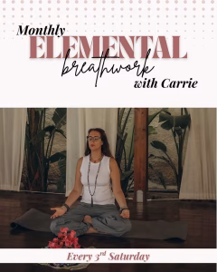 A promotional graphic for a Pittsboro Yoga class titled "Monthly Elemental Breathwork with Carrie," with "Every 3rd Saturday" along the bottom. The central photo shows a person seated cross-legged on a gray mat in a meditation posture, eyes closed, wearing glasses, a white tank top, gray pants, and a long beaded mala necklace, with hands resting open on the knees. Behind them is a warm-toned studio with large leafy plants, sheer curtains, and a wood post. A small cluster of pink flowers sits on the floor in front of the mat.